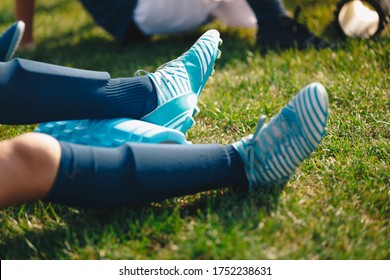 Kids On Training Session With Roller Foams. Children Soccer Football Players Stretching After Workout Training. Close-up Image Of Soccer Player Legs With Soccer Socks, Shin Pads And Cleats