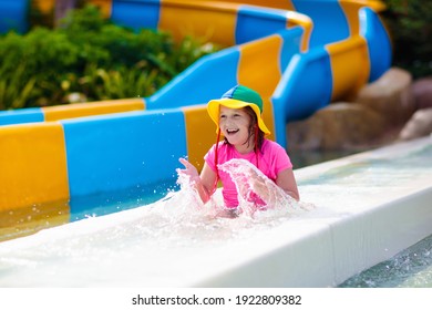 Kids On Water Slide In Aqua Park. Children Having Fun On Water Slides On Family Summer Vacation In Tropical Resort. Amusement Park With Wet Playground For Young Child And Baby.