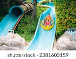 Kids on water slide in outdoor swimming pool. Family in aqua theme park. Children have fun in splash playground. Summer vacation with child. Kid on inflatable tube sliding into a pool.