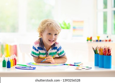 Kids Paint. Child Painting In White Sunny Study Room. Little Boy Drawing Rainbow. School Kid Doing Art Homework. Arts And Crafts For Kids. Paint On Children Hands. Creative Little Artist At Work.