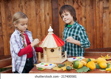 Kids Painting A Bird House In Autumn