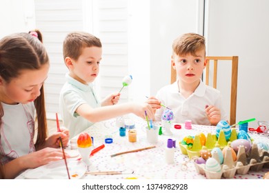 Kids painting eggs in the classroom, preparing for Easter. - Shutterstock ID 1374982928