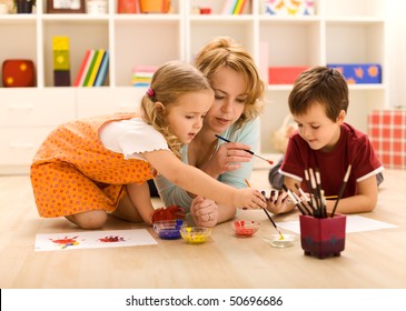 Kids painting hands and making prints with their mother sitting on the floor