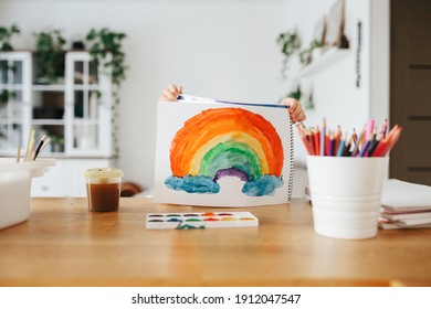 Kinder, die zu Hause am Tisch Regenbögen in Aquarellfarben malen. Kunst und Handwerk
