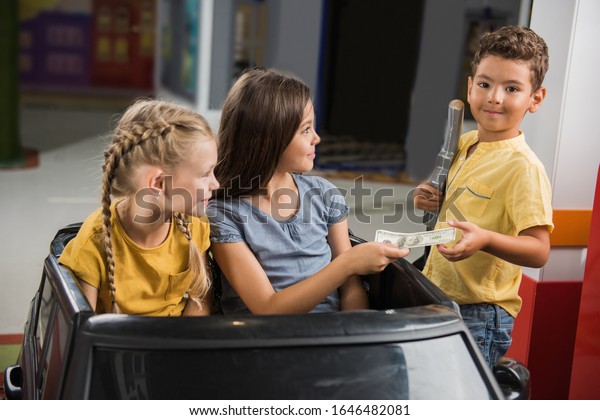 Kids\
paying money at toy petrol station. Child boy taking money and\
looking at camera. City of profession for\
children.