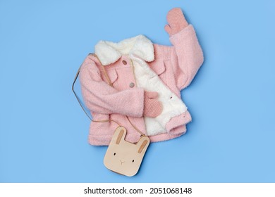 Kids pink fur jacket  with  cute bag on blue background. Stylish childrens outerwear. Winter fashion outfit 