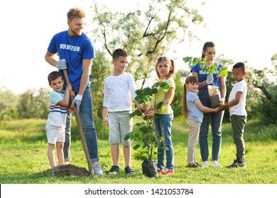 Kids planting trees with volunteers in park - Shutterstock ID 1421053784