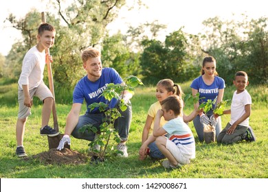 Kids Planting Trees With Volunteers In Park