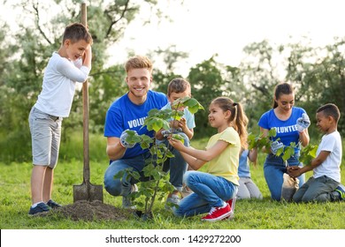 Kids Planting Trees With Volunteers In Park