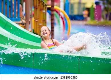 Kids Play In Aqua Park. Children At Water Playground Of Tropical Amusement Park. Little Girl At Swimming Pool. Child Playing At Water Slide On Summer Vacation In Asia. Swim Wear For Young Kid.