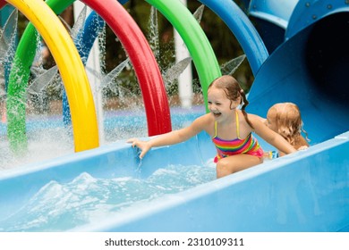 Kids play in aqua park. Children at water playground of tropical amusement park. Little girl and boy at swimming pool. Child playing at water slide on summer vacation in Asia. Swim wear for young kid.