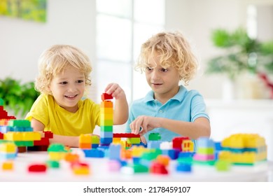 Kids play with colorful blocks. Little boy building tower at home or day care. Educational toy for young child. Construction creative game for baby or toddler kid. Mess in kindergarten playroom.