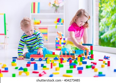 Kids Play At Day Care. Two Toddler Children Build Tower Of Colorful Wooden Blocks. Child Playing With Toy Train. Educational Toys For Preschool And Kindergarten.