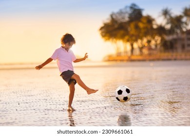 Kids play football on tropical beach at sunset. Cute little boy running with a ball. Travel with kids. Summer vacation on sea shore. Family holiday with children. Water sport fun. - Powered by Shutterstock