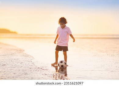 Kids play football on tropical beach at sunset. Cute little boy running with a ball. Travel with kids. Summer vacation on sea shore. Family holiday with children. Water sport fun. - Shutterstock ID 2311621097