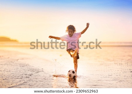 Kids play football on tropical beach at sunset. Cute little boy running with a ball. Travel with kids. Summer vacation on sea shore. Family holiday with children. Water sport fun.