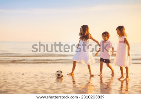 Kids play football on tropical beach at sunset. Cute little boy running with a ball. Travel with kids. Summer vacation on sea shore. Family holiday with children. Water sport fun.