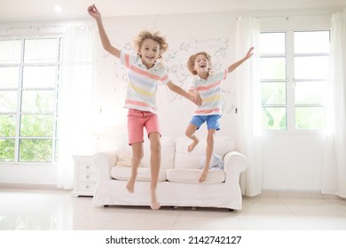 Kids Play At Home. Children Jump, Run And Dance. Active Boys Playing Tag, Running And Jumping On Couch In White Sunny House. Family Indoor Fun. Boy In Living Room. Activity And Movement Indoors.