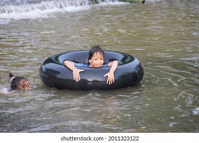 A Kids Play And Lying On A Tire Floating In Water Filmed In Chiang Mai, Thailand.