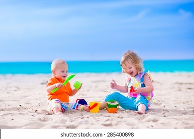 Kids Play On A Beach. Children Building Sand Castle On Tropical Island. Summer Water Fun For Family. Boy And Girl With Toy Buckets And Spade At The Sea Shore. Ocean Vacation With Baby And Toddler Kid.