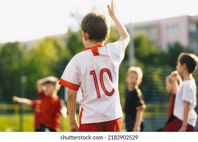 Kids Play Sports During School Physical Education Training. Elementary Age Children Play Sports On Summer Day. Young Boy Holding Hand Up Signaling Ball Pass