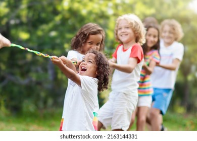 Kids Play Tug Of War In Sunny Park. Summer Outdoor Fun Activity. Group Of Mixed Race Children Pull Rope In School Sports Day. Healthy Outdoor Game For Little Boy And Girl.