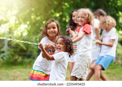 Kids play tug war in sunny park  Summer outdoor fun activity  Group mixed race children pull rope in school sports day  Healthy outdoor game for little boy   girl 