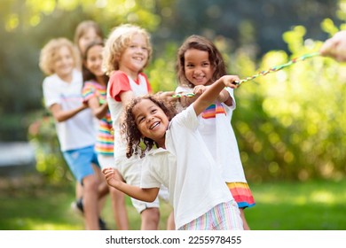 Kids play tug of war in sunny park. Summer outdoor fun activity. Group of mixed race children pull rope in school sports day. Healthy outdoor game for little boy and girl. - Powered by Shutterstock
