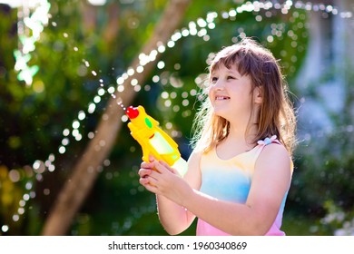 Kids Play With Water Gun Toy In Garden. Outdoor Summer Fun. Little Boy Playing With Water Hose In Sunny Backyard. Party Game For Children. Healthy Activity For Hot Sunny Day.