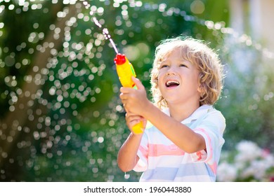 Kids Play With Water Gun Toy In Garden. Outdoor Summer Fun. Little Boy Playing With Water Hose In Sunny Backyard. Party Game For Children. Healthy Activity For Hot Sunny Day.