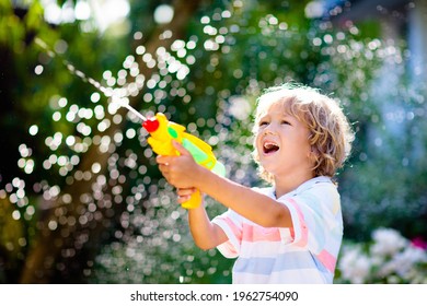Kids Play With Water Gun Toy In Garden. Outdoor Summer Fun. Little Boy Playing With Water Hose In Sunny Backyard. Party Game For Children. Healthy Activity For Hot Sunny Day.