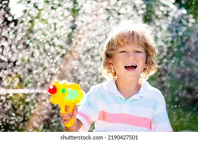 Kids Play With Water Gun Toy In Garden. Outdoor Summer Fun. Little Boy Playing With Water Hose In Sunny Backyard. Party Game For Children. Healthy Activity For Hot Sunny Day.