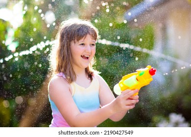 Kids Play With Water Gun Toy In Garden. Outdoor Summer Fun. Little Boy Playing With Water Hose In Sunny Backyard. Party Game For Children. Healthy Activity For Hot Sunny Day.