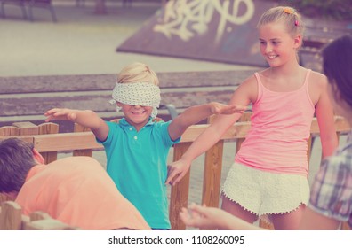 Kids are playing in blindfolders on the playground.
