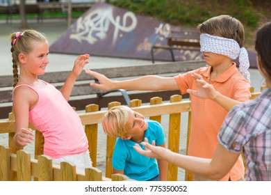 Kids are playing in blindfolders on the playground.