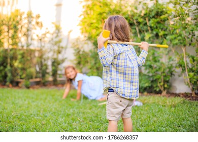 Kids Playing Croquet On Grass Yellow Stick And Ball