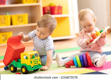 Kinder, die mit Lernspielzeug spielen. Kinder sitzen auf einem Teppich in einem Spielzimmer zu Hause oder im Kindergarten. Kleinkinderjunge mit Kinderwagen und Kleinkind mit Ringen.