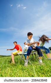 Kids Playing Game And Sit Fast On Chairs Outside