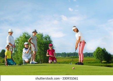 Kids playing golf by putter on green