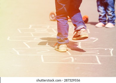 kids playing hopscotch on playground outdoors, children outdoor activities