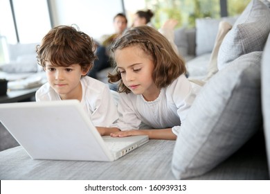 Kids Playing With Laptop Computer At Home