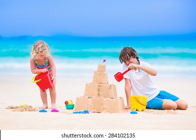 Kids Playing On A Beach. Two Children Build A Sand Castle At The Sea Shore. Family Vacation On A Tropical Island. Boy And Girl Digging With Toy Spade And Kid Spade. Traveling With Young Child.