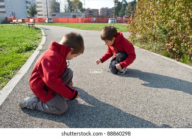 Kids Playing On The Ground With Chalk.