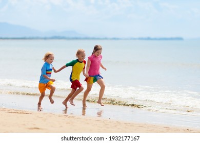 Kids Playing On Tropical Beach. Children Swim And Play At Sea On Summer Family Vacation. Sand And Water Fun, Sun Protection For Young Child. Little Boy Running And Jumping At Ocean Shore.