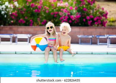 Kids Playing At Outdoor Swimming Pool. Little Girl And Boy Play And Swim In Resort Pool On Tropical Beach Island Summer Family Vacation. Swim And Eye Wear, Sun Protection, Water Toys For Children. 