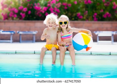 Kids Playing At Outdoor Swimming Pool. Little Girl And Boy Play And Swim In Resort Pool On Tropical Beach Island Summer Family Vacation. Swim And Eye Wear, Sun Protection, Water Toys For Children