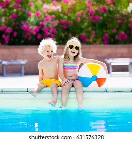 Kids Playing At Outdoor Swimming Pool. Little Girl And Boy Play And Swim In Resort Pool On Tropical Beach Island Summer Family Vacation. Swim And Eye Wear, Sun Protection, Water Toys For Children. 