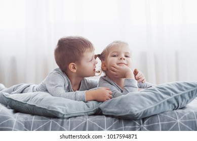 Kids Playing In Parents Bed. Boy And Girl In Matching Pajamas. Sleepwear And Bedding For Child, Family Morning.