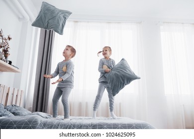 Kids Playing In Parents Bed. Boy And Girl In Matching Pajamas. Sleepwear And Bedding For Child, Family Morning.