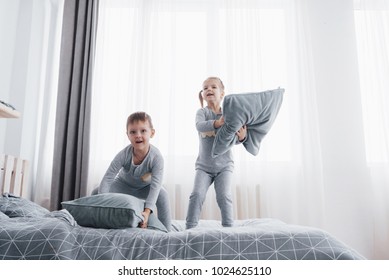 Kids Playing In Parents Bed. Boy And Girl In Matching Pajamas. Sleepwear And Bedding For Child, Family Morning.